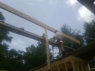 Carpenter setting a ridge beam over a new addition frame — Ice Dam Removal by Roofing Brothers in Tuskegee