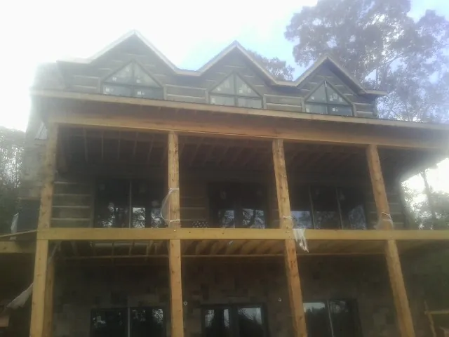 Dormers and porch framing on a large log home under construction — Roof Coating work by our crew in Tuskegee