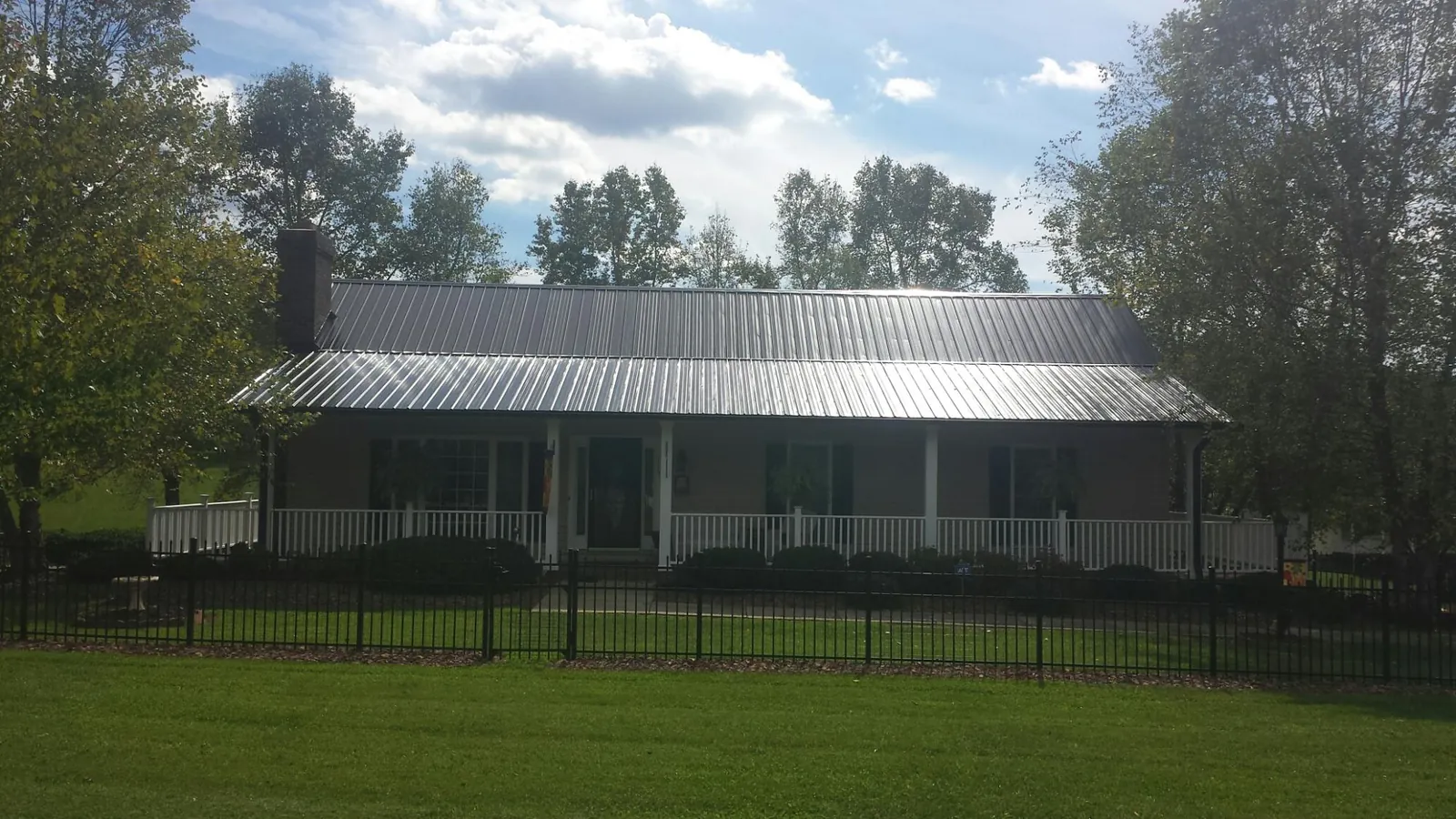 Gray metal roof on a brick ranch with a full width front porch — Gutter Guard Installation work by our crew in Tuskegee