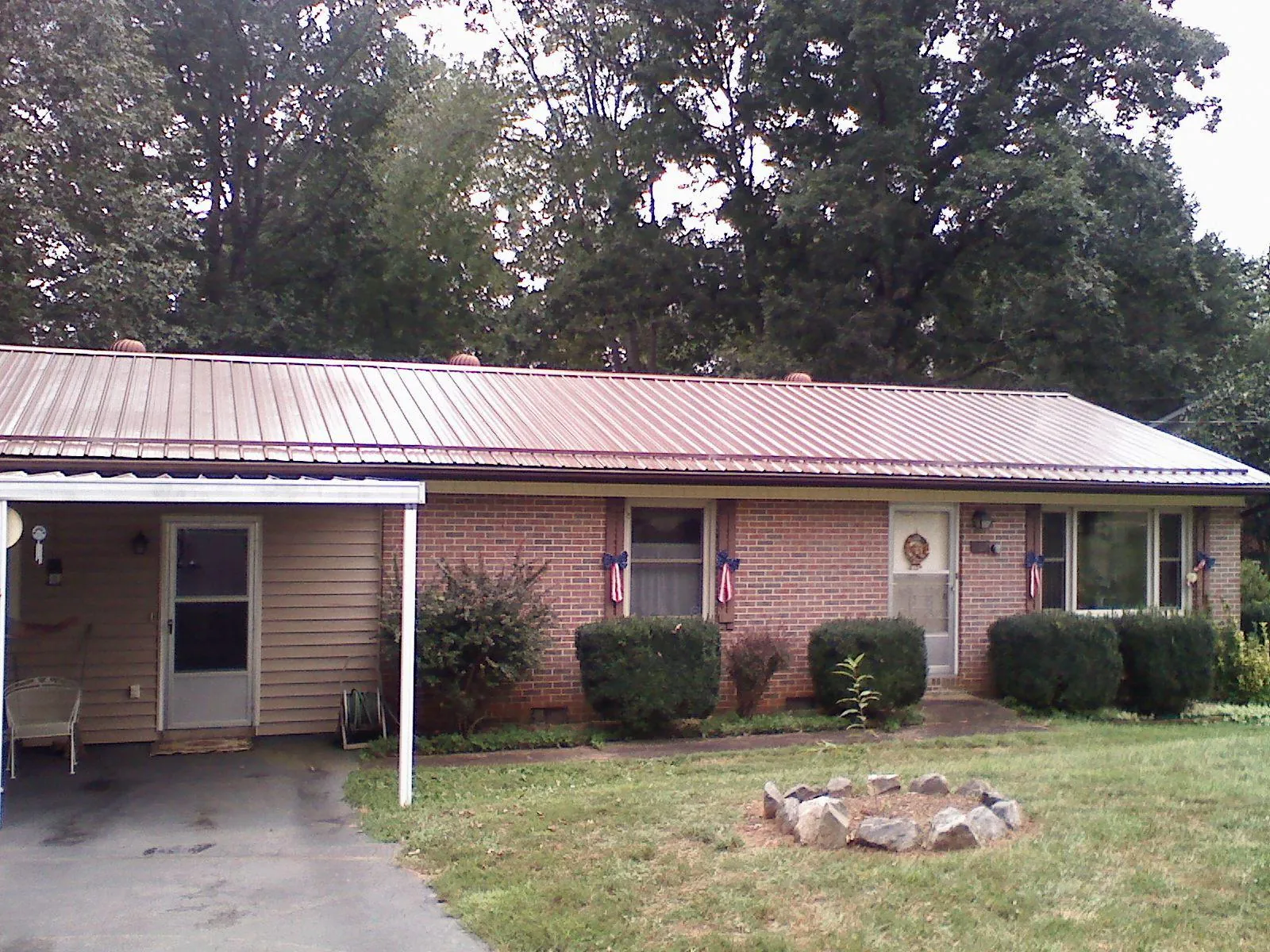 Bronze metal roof and carport on a brick ranch home — Roof Repair work by our crew in Tuskegee