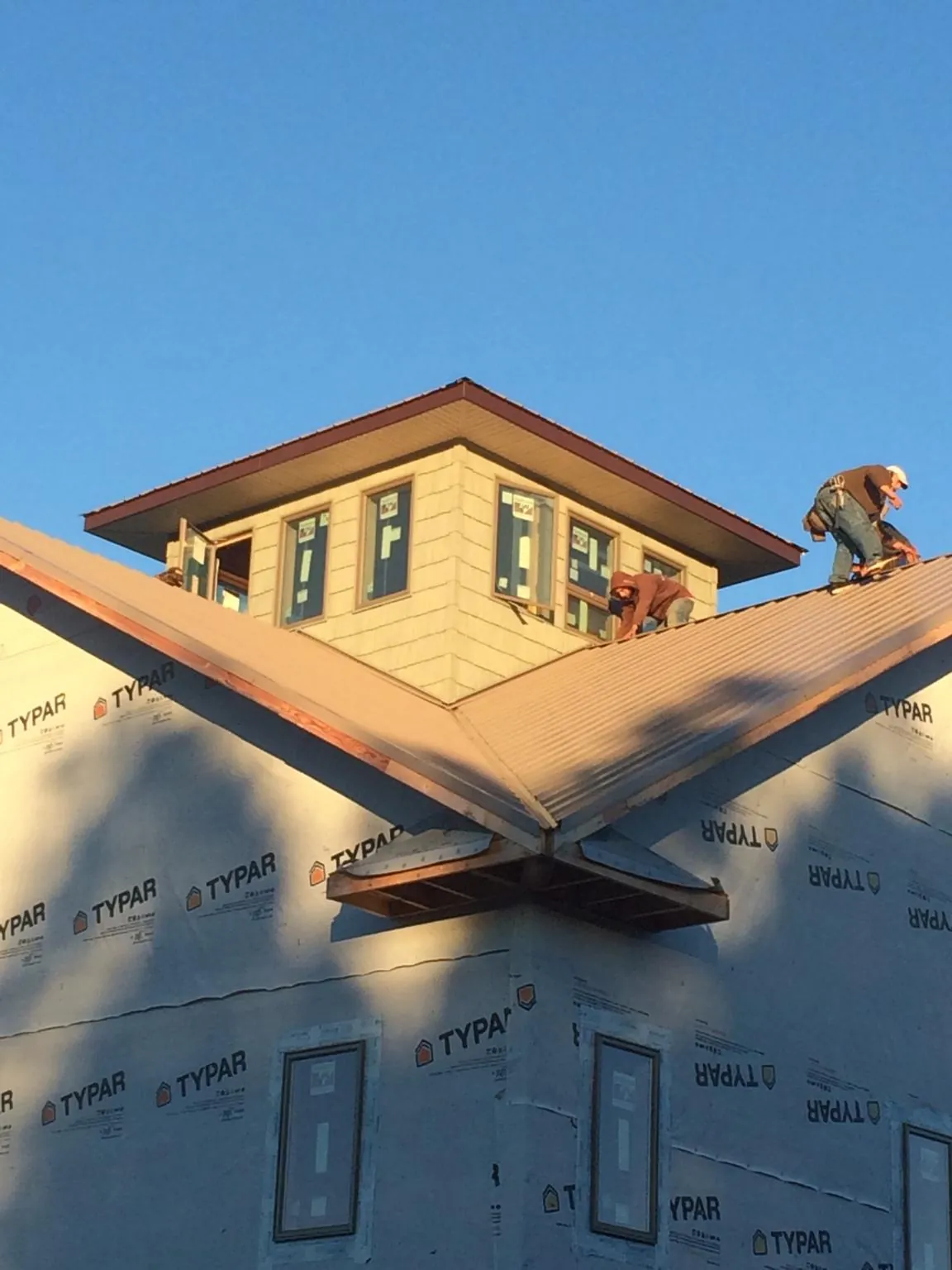 Roofers working around a rooftop cupola on a new metal roof at sunset — Roof Waterproofing in Tuskegee by Roofing Brothers